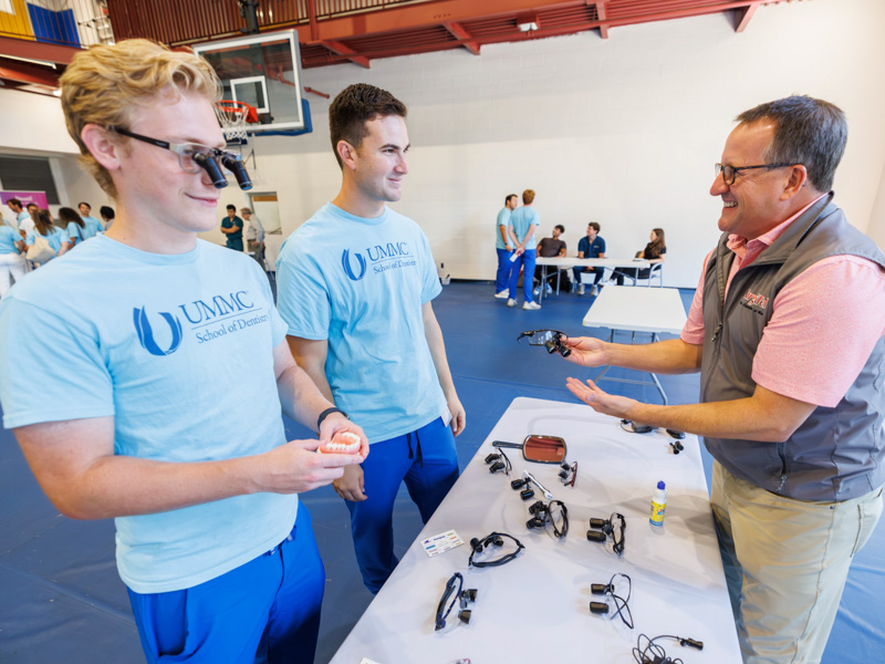 First-year dental students Christopher Cronin, left, and Caden Grover, try on surgical glasses with manufacturer representative Scott Walker during the student organization fair at the Norman C. Nelson Student Union.