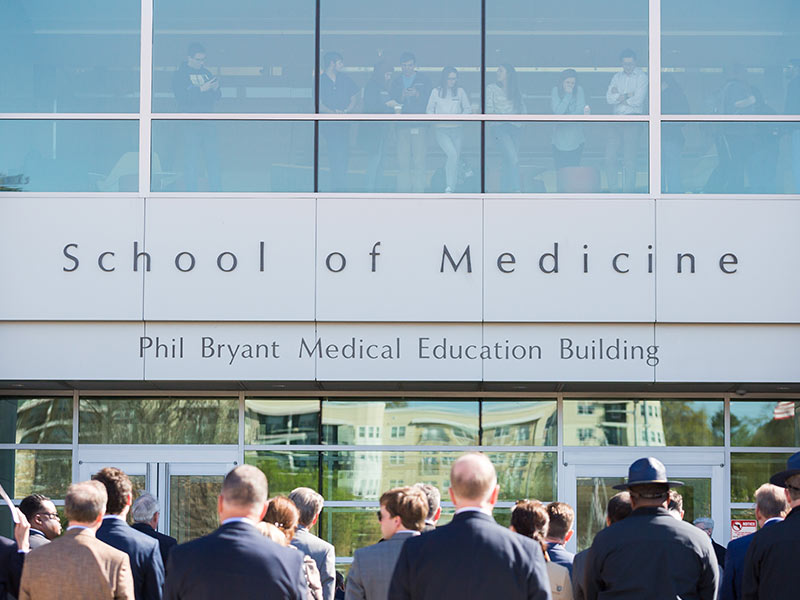 As a chilly wind whipped the crowd gathered outside for the unveiling of the Phil Bryant Medical Education Building, Gov. Bryant called attention to dozens of medical students who lined five stories of windows inside the building. “They seem somewhat tired and stressed,” he joked.