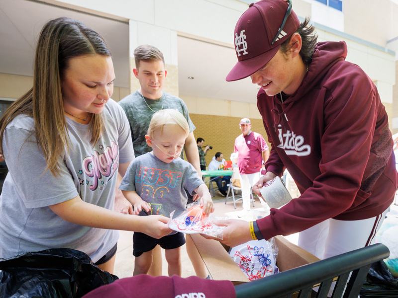 Michael Tew, of Meridian, a patient at Children's of Mississippi, and his mother, Bailey Tew, visit with MSU pitcher Tyson Hardin during the team's visit to the facility.