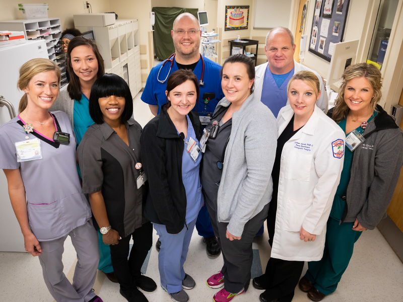 UMMC staff on 5 North include, front row, left to right, registered nurse Molly Ables, housekeeper Tarita Weathersby, nurse graduate Erin Hicks, registered nurse Emily Jones, nurse practitioner LeAnne Adcock, physical therapist Kristin Lang; and back row, left to right, hospital tech Lauren Habig, School of Medicine clinical instructor in orthopedic surgery Brad Martin and registered respiratory therapist Race Robinson. Sneaking a peek (background right) is registered nurse Beth Efrem.