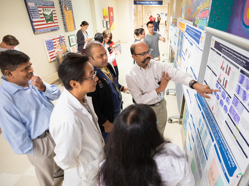 Among those reviewing a research poster are, from left, Dr. Abhay Bhatt, Dr. Yi Pang, Dr. Chirag Talati, Dr. Sumara Ramararo and Dr. Pradeep Alur.