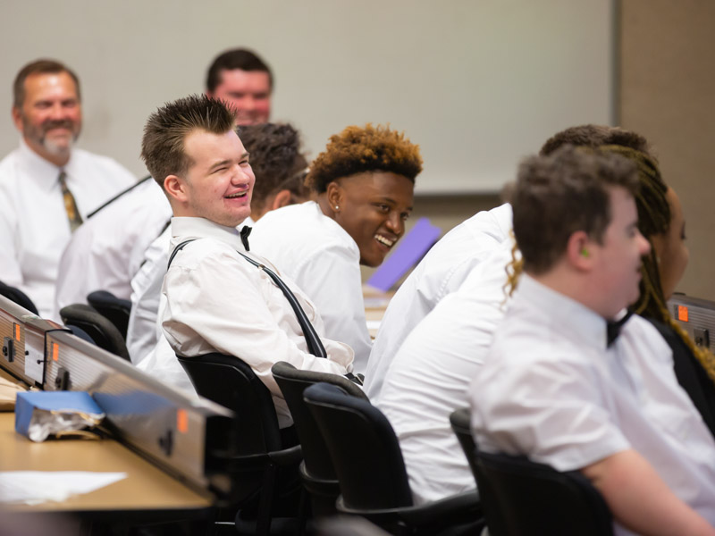 Project SEARCH participants, including Taton Wetzel, center left, and Joshua Wilson, center right, laugh during their program graduation ceremony May 17.