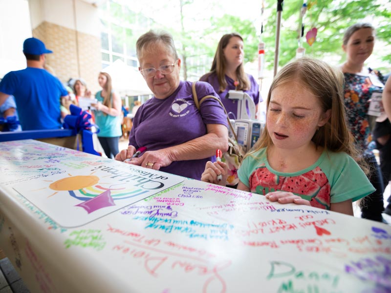 Sylvia Martin watches granddaughter Mackynlee Bedwell of Foxworth, a Batson patient, sign the beam that will be placed at the top of UMMC's pediatric expansion.