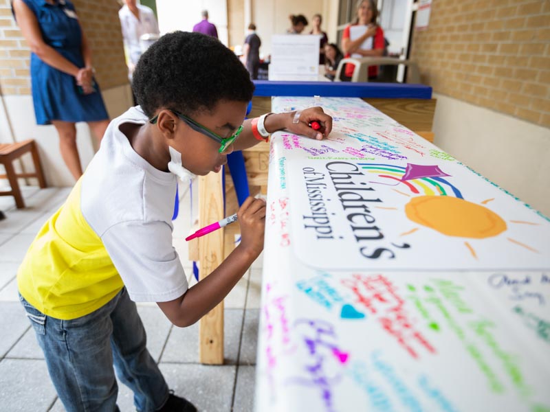 Batson patient Tayden Franklin of Meridian signs the beam during Thursday's signing party in the Rainbow Garden.