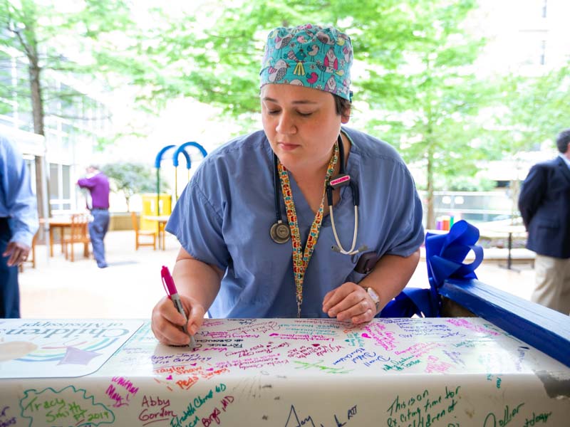 Pediatric Anesthesiologist Sara Robertson signs the beam at the Rainbow Garden signing party June 6.