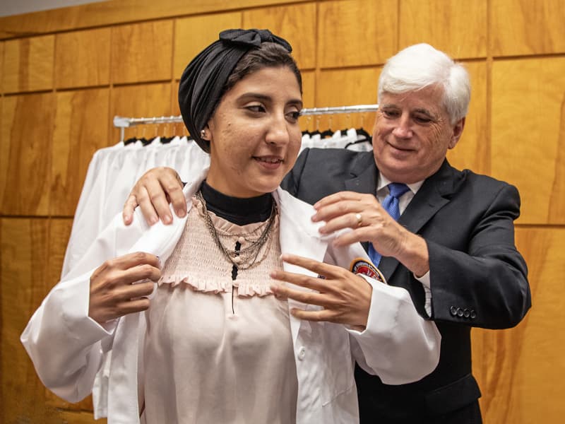 Incoming Ph.D. student Aya Ali receives her lab coat from Dr. Joey Granger at the School of Graduate Studies in the Health Sciences' White Coat Ceremony.