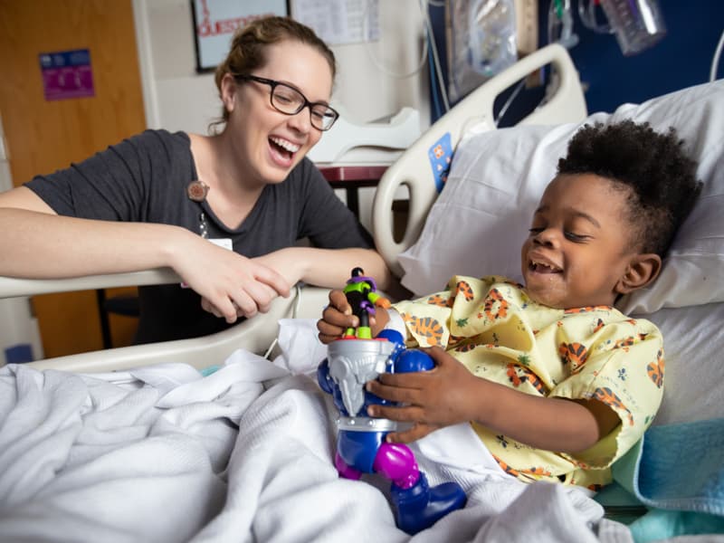 Madeline Wilson, Children's of Mississippi Child Life specialist, laughs with Keidron Hall of Gulfport during his hospital stay.