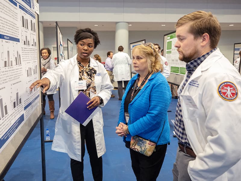 Dr. Barbara Alexander, center, the 2019 School of Graduate Studies in the Health Sciences Distinguished Alumna, talks to Ph.D. students Olivia Travis, and Corbin Shields during SGSHS Research Day.