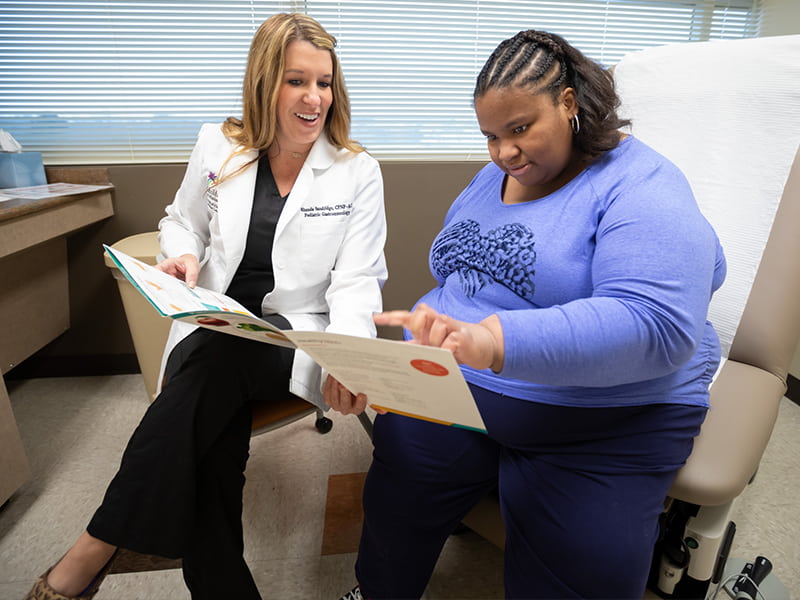 Nurse practitioner holds open a meal choice pamphlet to a patient while the patient points.