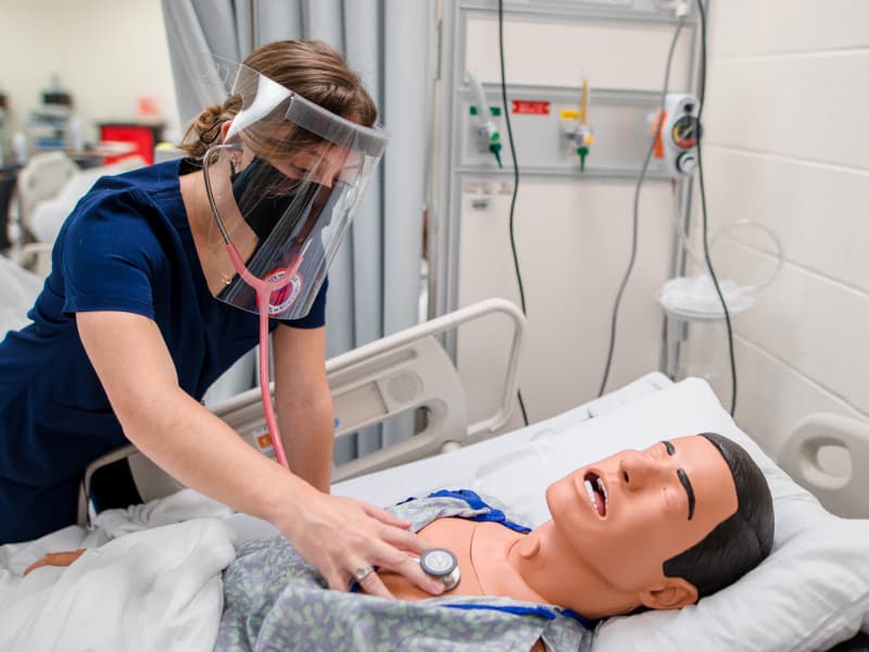 Alexandra Tzotzolas, a School of Nursing student, wears a face shield and maintains her distance from other classmates while she listens to the heart and lungs of a mannequin in the SON’s simulation lab. Students in all seven UMMC schools who venture onto campus this fall will have to adhere to specific safety guidelines.