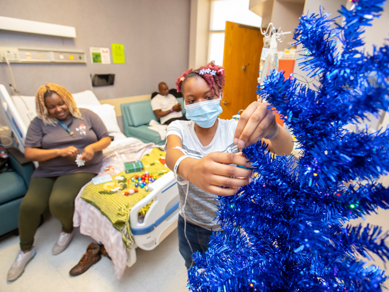 Children's of Mississippi patient Melanie Conner of Clinton decorates her hospital room Christmas tree following a visit to BankPlus Presents Winter Wonderland. Looking on are her parents, Monika and Dewayne Conner.