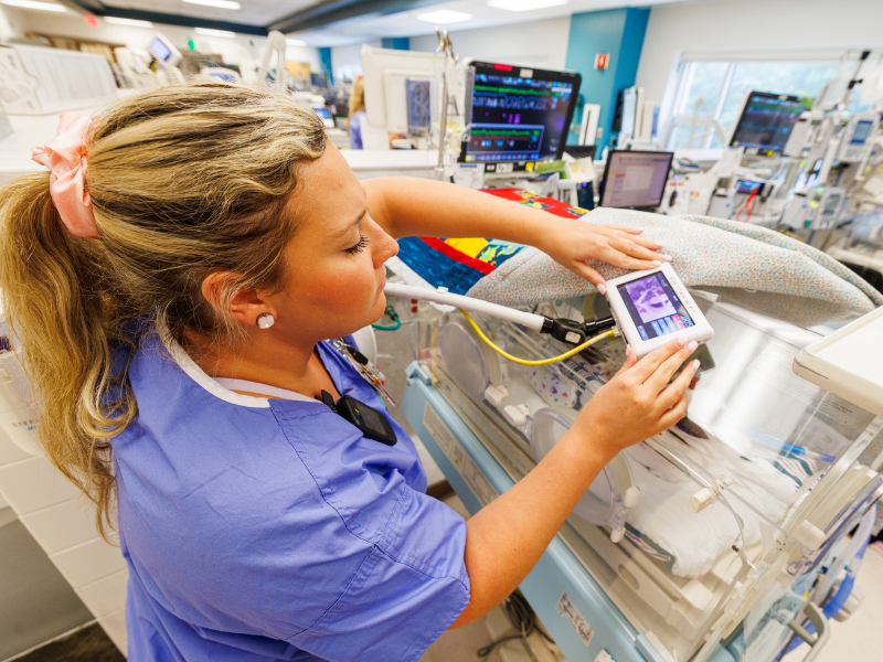 Registered nurse Caroline Meyers adjusts the AngelEye camera at patient Deuce Matthews' bedside.