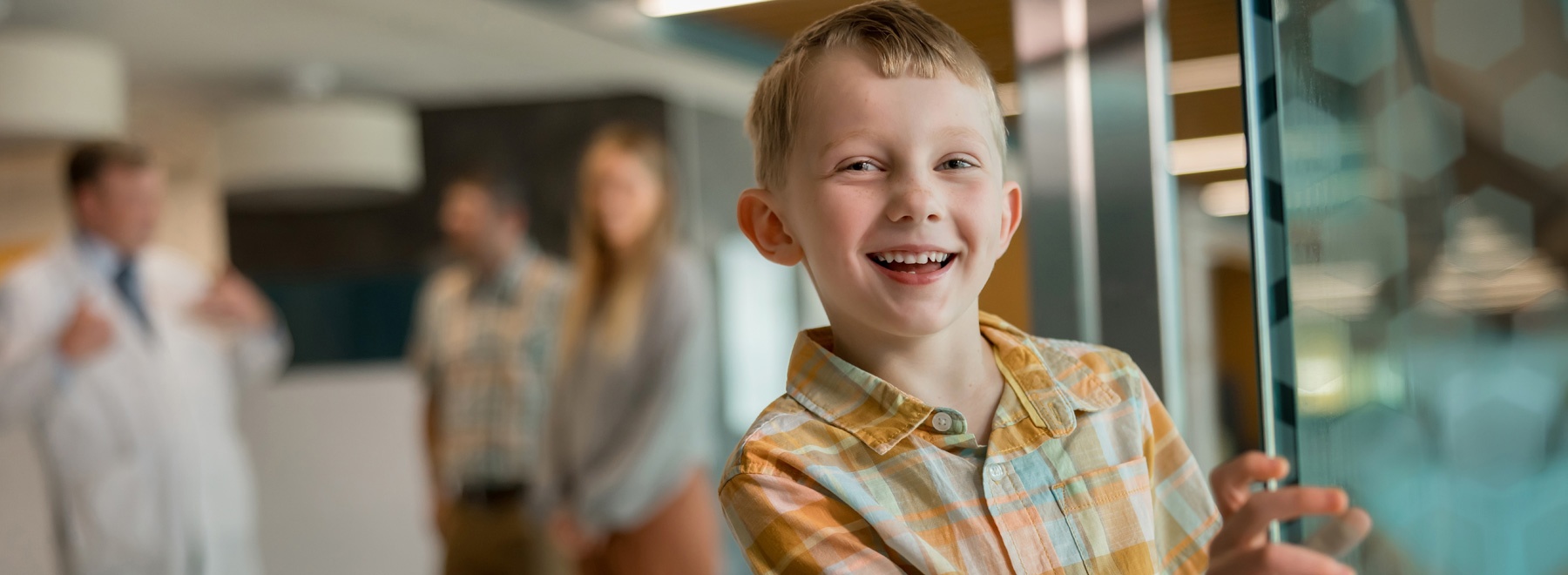 Child peeks around corner while smiling.