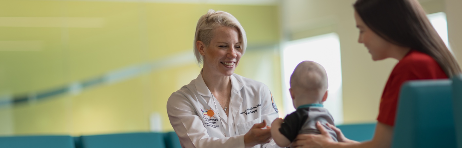 Medical Provider smiles while reaching out to baby.