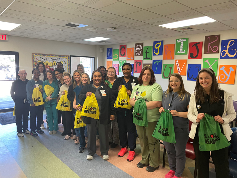 Group portrait of Child life staff members holding toy goody bags.