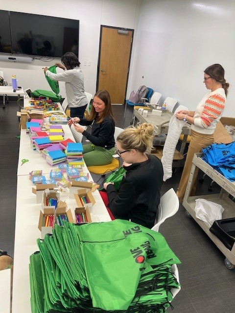 Child Life staff members working at a table to fill goody bags with toys.