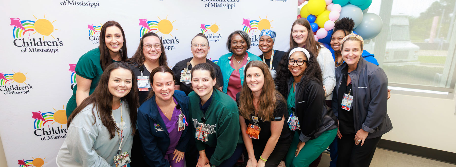 Pediatric nurses smile in front of a banner with the Children's of Mississippi logo. Superimposed over the image is the Magnet Recognition Program logo.