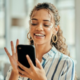 Woman smiles while typing on smart phone.