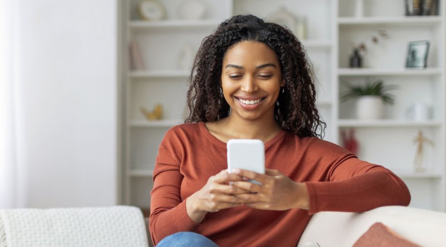 Woman smiles while looking at her phone.