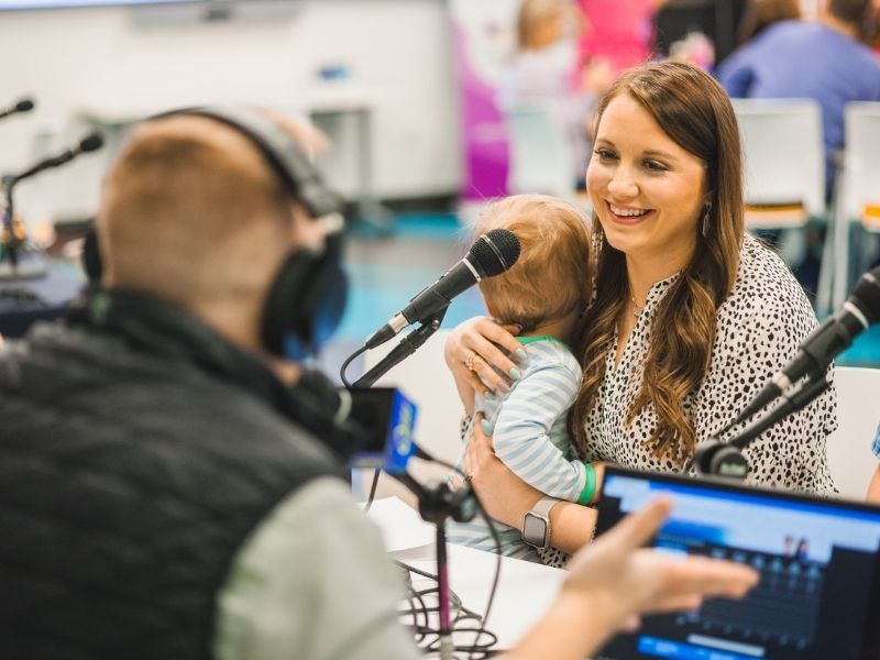 Nikki Neely holds son Charlie while doing an interview with Ryan Johnson of Q101.