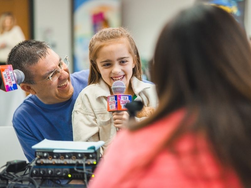 Children's of Mississippi patient Emma Eubank of Petal does an interview with Traci Lee on US 96.3 as her dad, Brad, looks on.