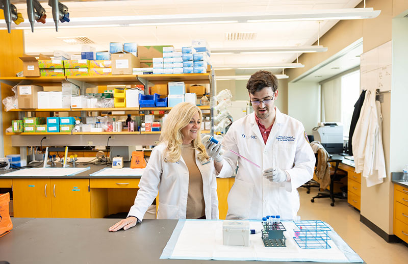 Research lab. Two researchers in white lab coats work together with laboratory equipment and test tubes in a bright research lab.