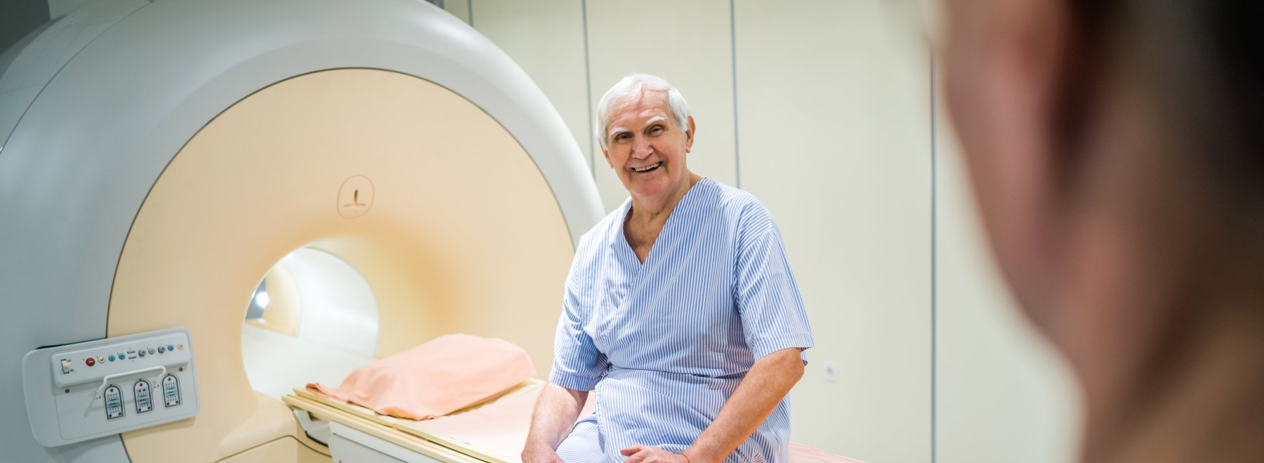 Smiling patient sits on gamma knife equipment before radiation therapy.
