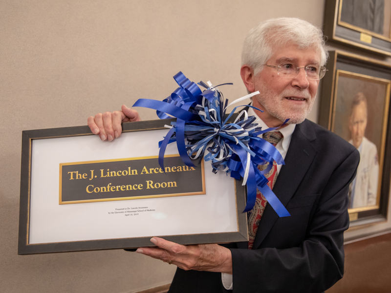 Dr. Lincoln Arceneaux accepts a framed representation of the plaque marking the room named for him.