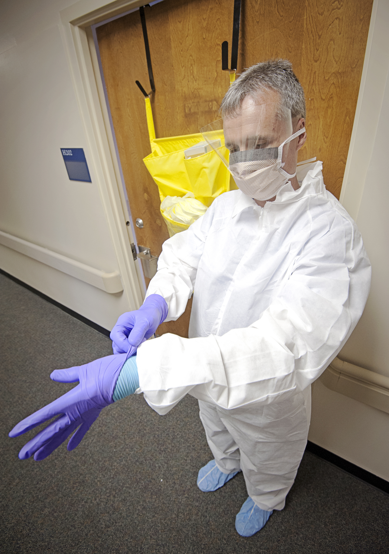 University of Mississippi Medical Center infection preventionist Morris Ainsworth dons two pairs of gloves after putting on a face shield, face mask, shoe coverings and what's called a protective "bunny suit" that health-care providers must wear when caring for patients with communicable diseases, including if necessary the deadly Ebola virus.