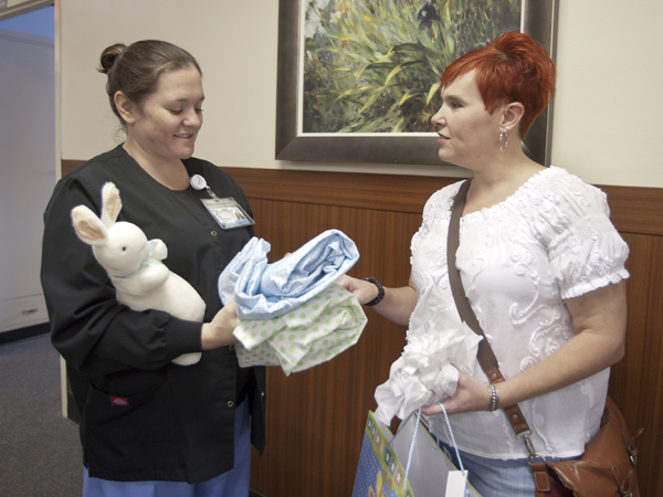 Battle, right, a year and eight months after receiving a new liver, gives her transplant coordinator Katherine Savoy a gift in preparation for the birth of Savoy's baby.