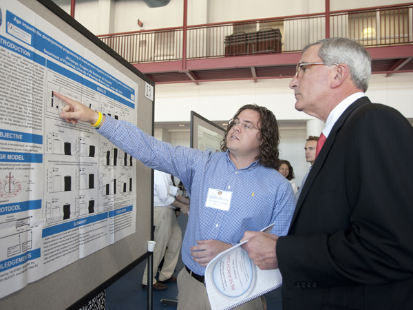 John Henry Dasinger, left, UMMC graduate assistant, explains his research project to Dr. Dzielak during the School of Graduate Studies in the Health Science Research Day.