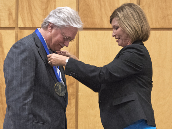 Dr. LouAnn Woodward, right, vice chancellor for health affairs and dean of the school of medicine, hangs the Billy S. Guyton Distinguished Professor medallion on Dr. Richard Summers, associate vice chancellor for research.
