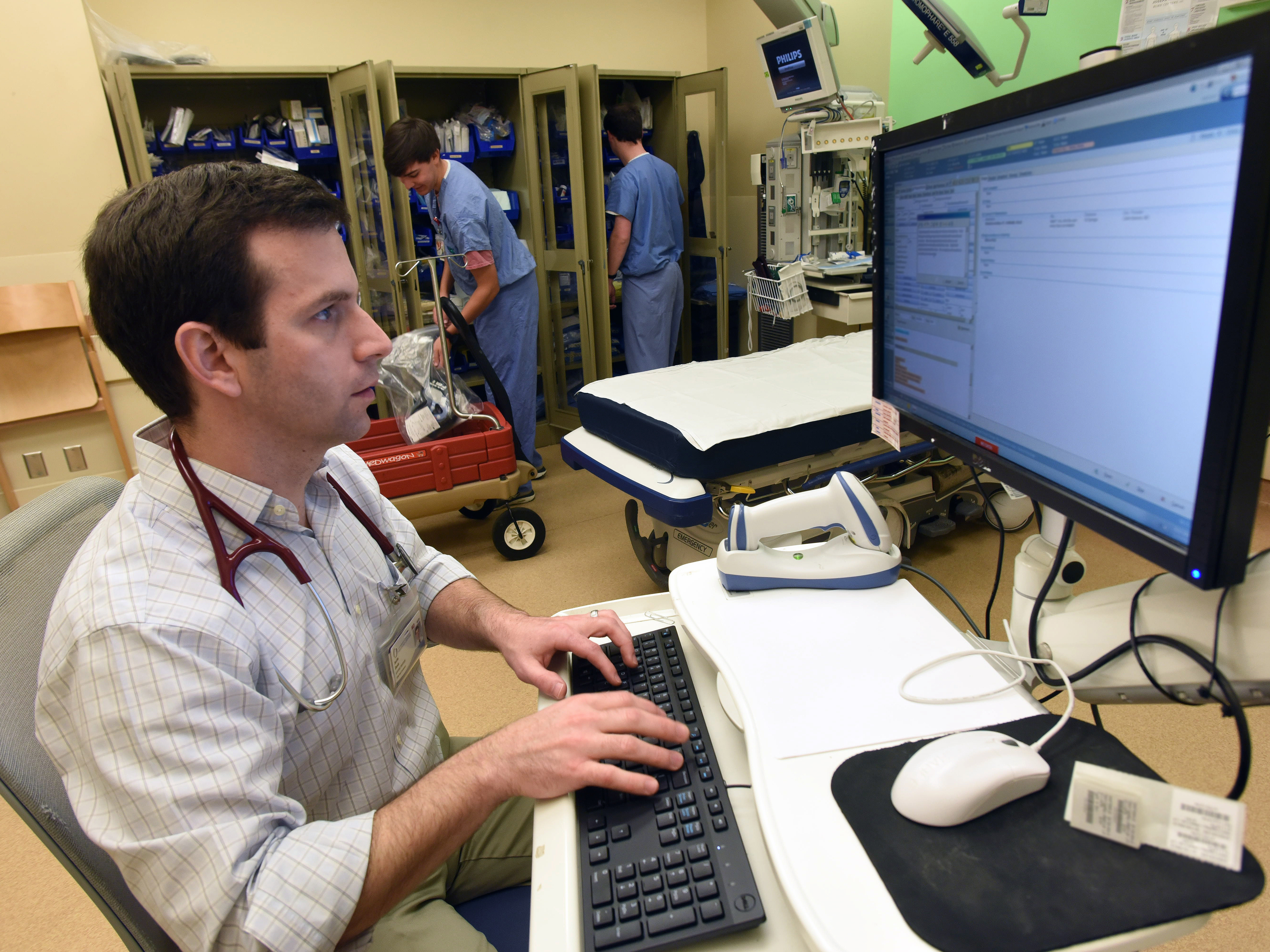 Dr. Justin Davis, assistant professor of pediatric emergency medicine, examines a patient's health records in the pediatric emergency department. A new information exchange with the Division of Medicaid allows him to also access those patient records.