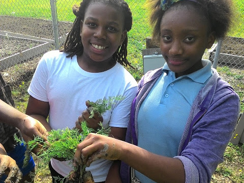 Shelby Middle School students proudly show off vegetables grown in their school garden.