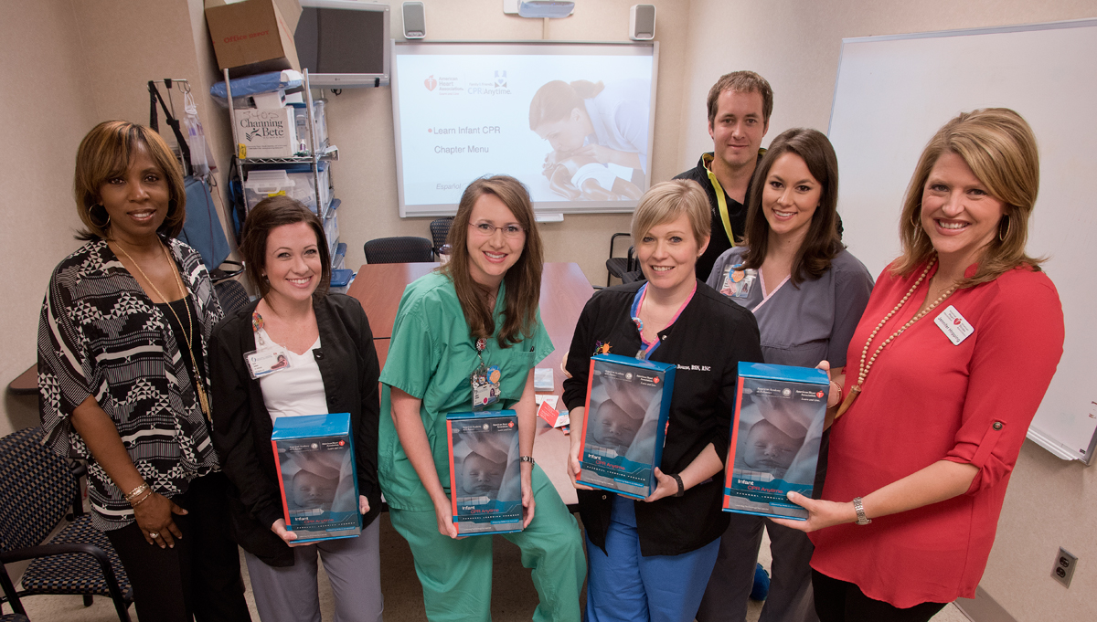 The American Heart Association is donating about a year's supply of infant CPR kits to UMMC to use in training parents in classes. Showing a few of the more than 1,100 kits are, from left, American Heart Association Community Health Director Rosa Wilson, nurses Erin Jones, Ashley Stegall, Amanda Bourne, Billy Needham and Emily Thompson, and Jennifer Hopping, vice president of the Greater Southeast Affiliate of the American Heart Association.