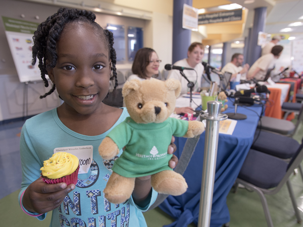Malia Croom receives a cupcake and a new friend, a Heritage Properties "Blair Bear" during her Radiothon appearance.
