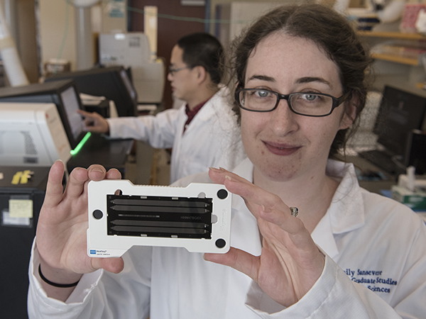 Emily Sansevere, a fifth-year graduate student, displays a genome sequencing chip. By loading millions of DNA fragments on a chip, she can then determine the entire genetic sequence, or genome, of a bacteria such as Staphylococcus aureus.