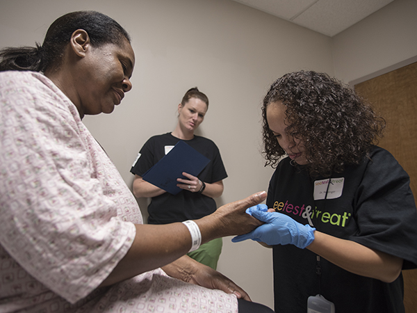 Dr. Jasmine Hollinger, assistant professor of dermatology, examines Willie Perkins of Jackson for signs of acral melanoma while Ashley May, an LPN in the dermatology department, stands ready with the ever-present paperwork.