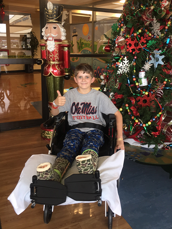 Felton gives a "thumbs-up" sign in front of the Batson Children's Hospital's Christmas tree while recovering from major orthopaedic surgery last December.