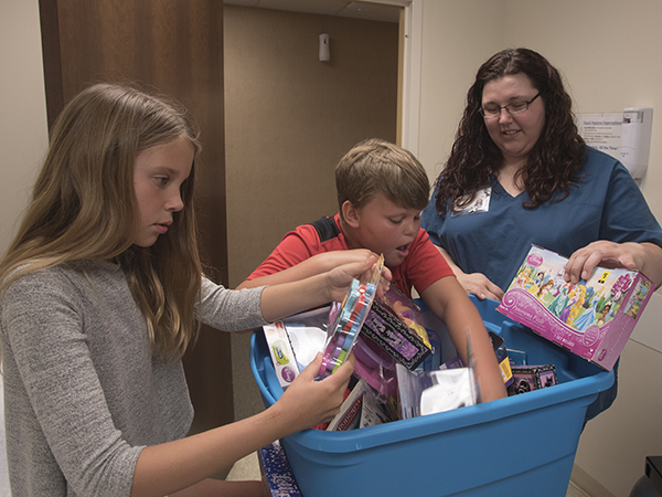 Amber Taylor, right, a licensed practical nurse at Lakeland Family Medicine, helps twins Jordyn and Justice Burgemaster of Madison choose a toy from a box from an assortment collected by Taylor.