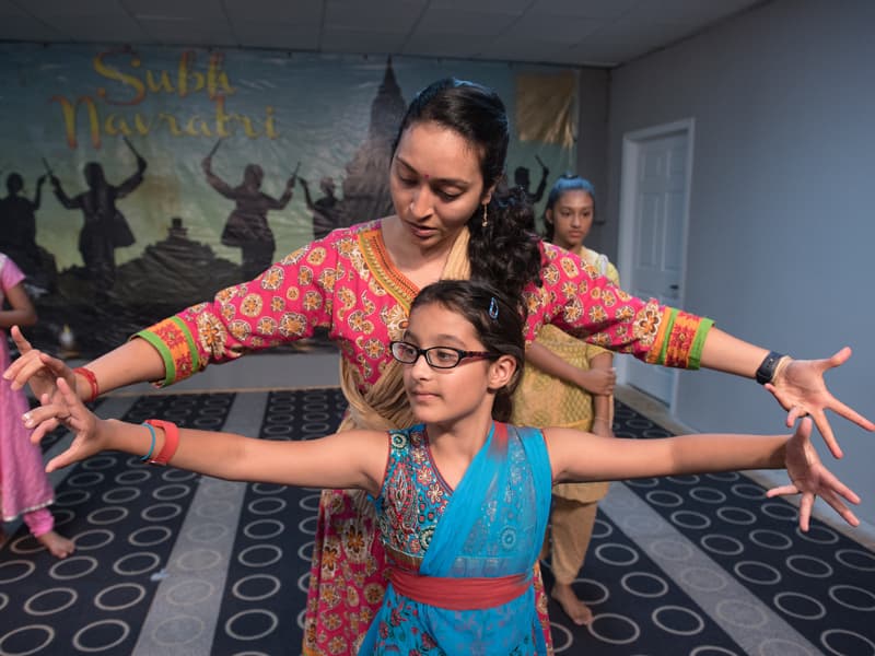 Deepti and student Shreya Tandon practice a dance move while rehearsing the traditional Indian dance Bharatnatyam for the upcoming Diwali festival celebration.