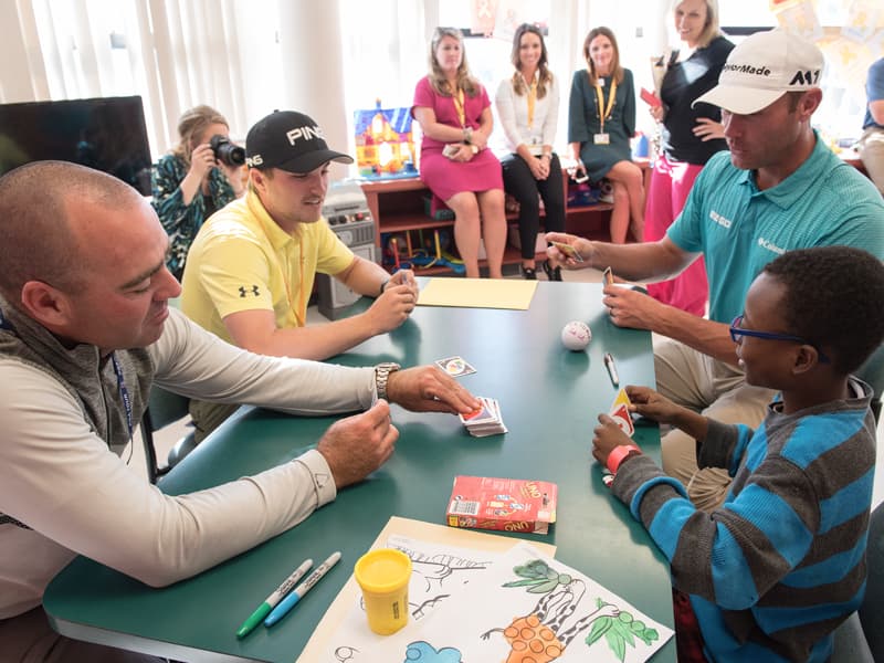 PGA golfers, from left, Ryan Armour, Austin Cook and Shawn Stefani fall victim to Batson Children's Hospital patient Keydarius Taylor's UNO skills during a visit Tuesday.