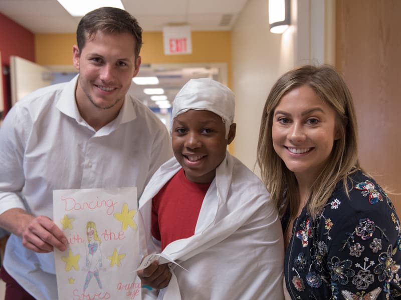 Batson Children's Hospital patient Orenzo Dye of Greenville shows a "Dancing with the Stars" drawing he made for Shawn Johnson East, a winner of the television ballroom dancing competition. At left is East's husband, professional football player Andrew East.