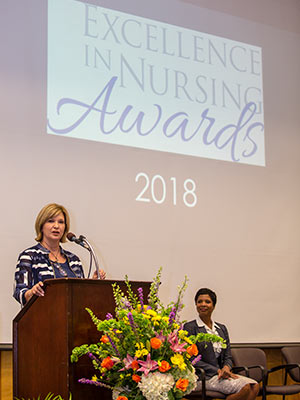 Dr. LouAnn Woodward, vice chancellor for health affairs and dean of the School of Medicine, speaks during the annual Excellence in Nursing Awards. Looking on is Dr. Tonya Moore, administrator of community health services for UMMC's Center for Telehealth.