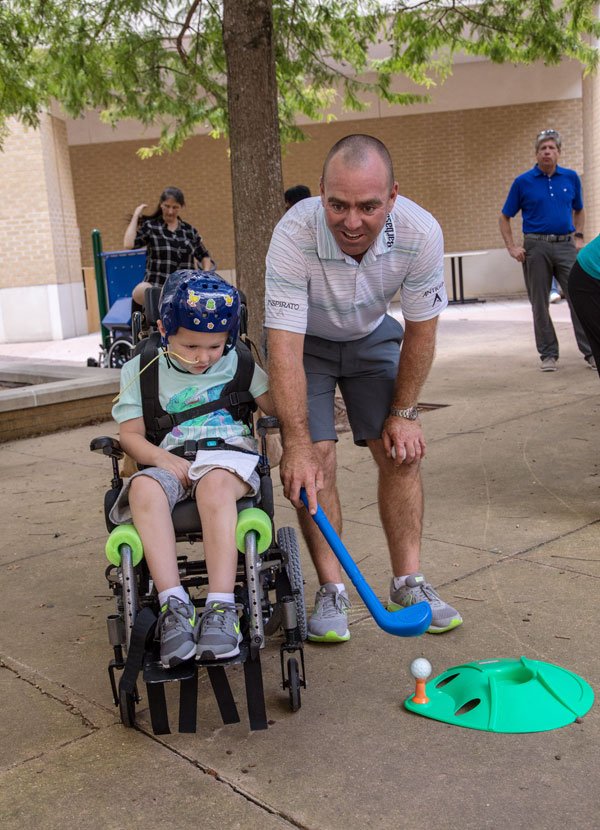 Batson Children's Hospital patient Peyton Homan of Greenville gets a lesson from PGA TOUR golfer Ryan Armour.