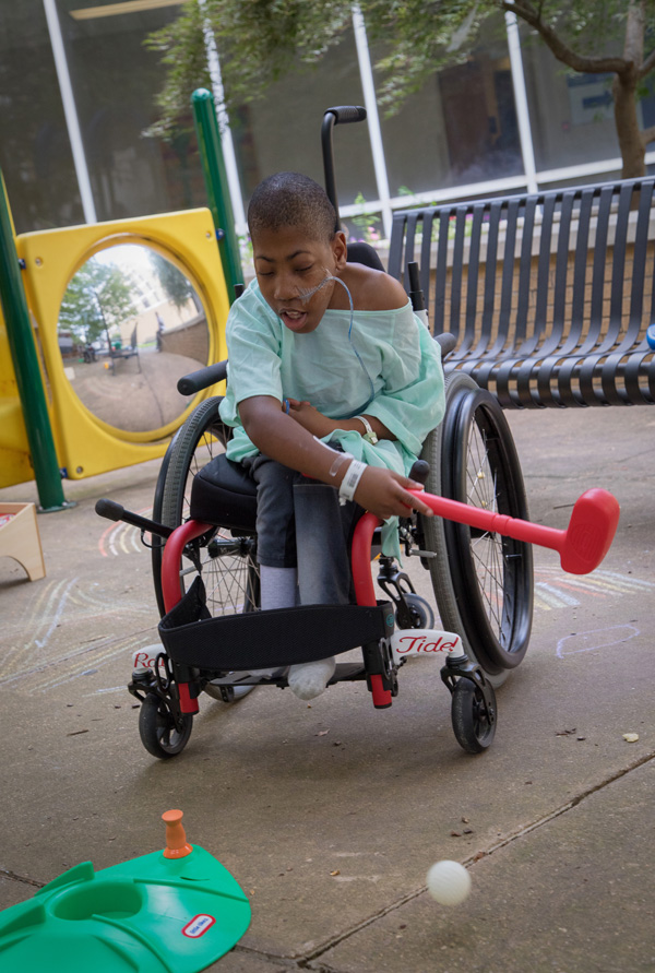 Batson Children's Hospital patient Zarian Phlegm of Poplarville takes a swing at a golf ball in the Rainbow Garden. He made several hole-in-ones during the afternoon of outdoor fun Monday.