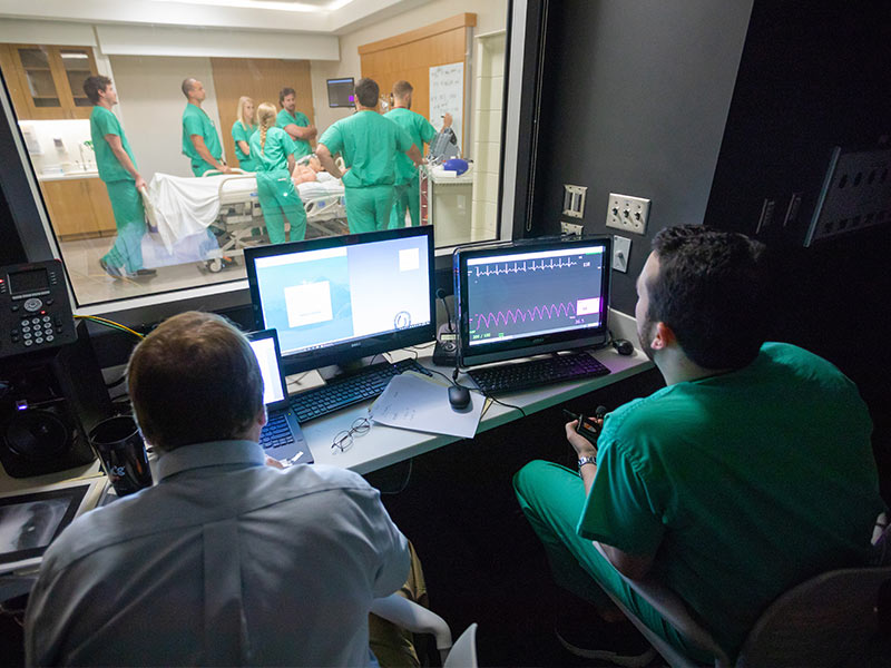 Dr. Jeffrey Orledge, left, and Dr. Jeremy Benoit, a third-year resident, manipulate vital statistics for the simulated patient being observed by a group of Emergency Medicine interns.