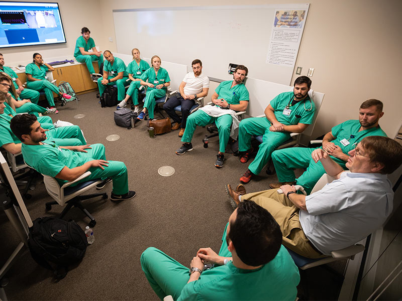 Orledge, right, conducts a debriefing session with Emergency Medicine residents.