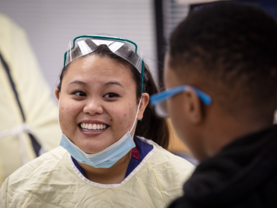 Dr. Mauren Malingkas, first-year dental resident, smiles as she chats with a student after his dental exam.