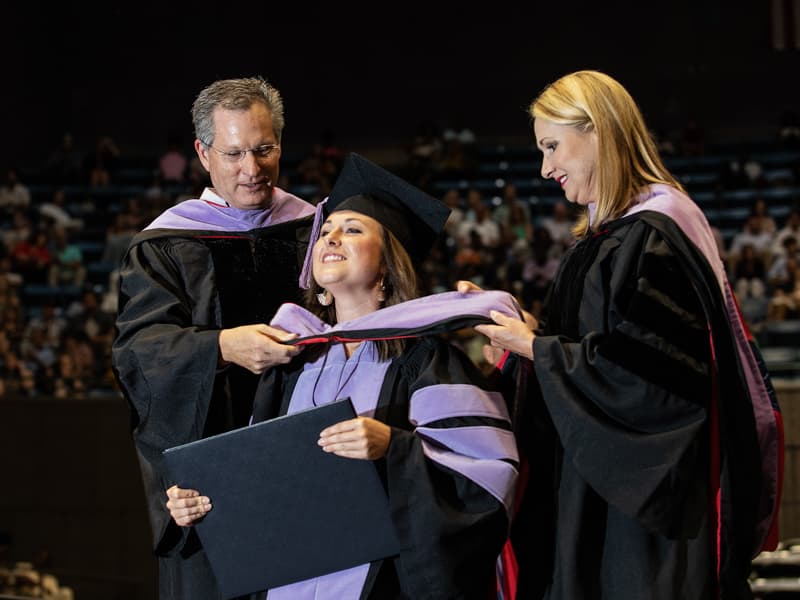 Dr. Alan Lucas, left, and his wife, Dr. Melinda Lucas, hood their daughter, Meredith Lucas, as she receives the Doctor of Dental Medicine. Her parents are alumni of the School of Dentistry.